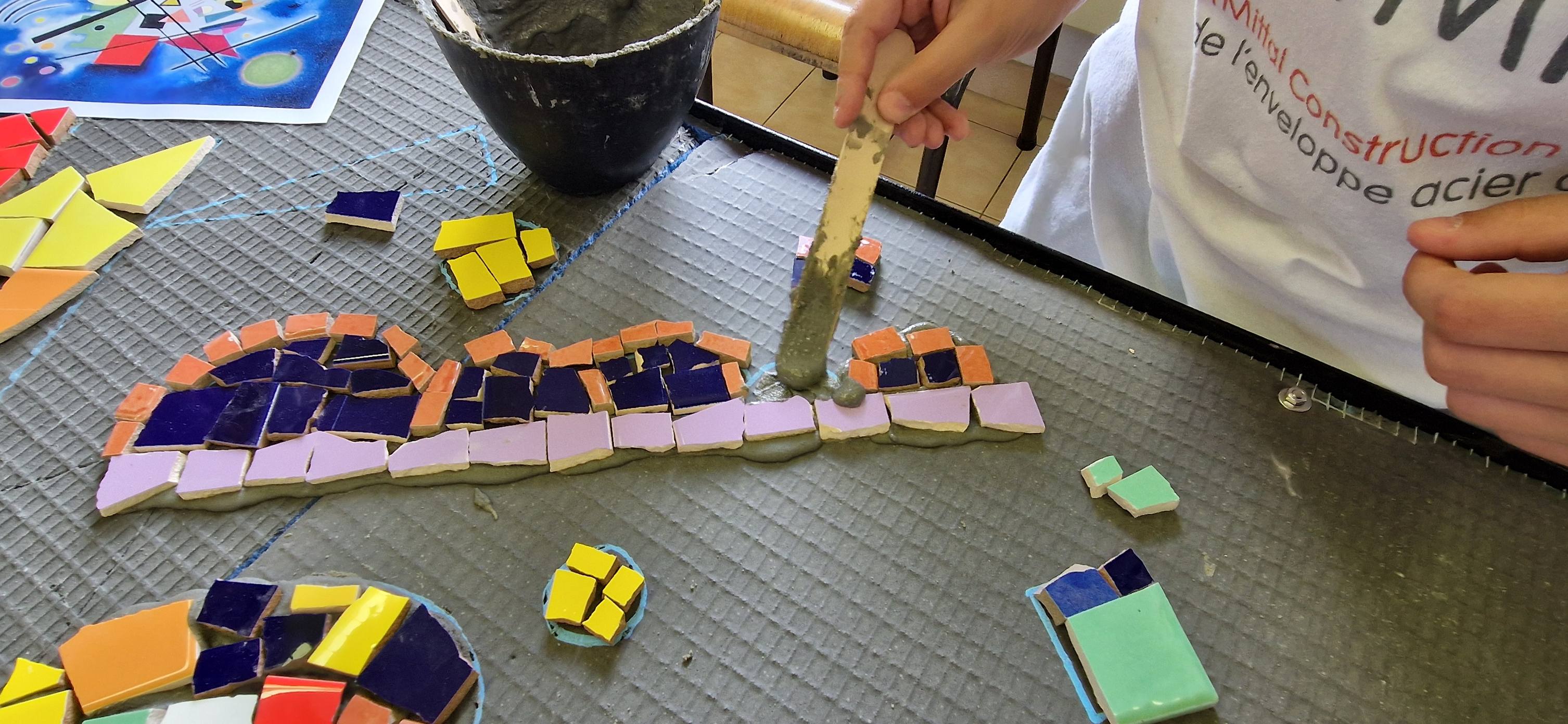 mains d'enfants qui font une activités artistique type mozaïques