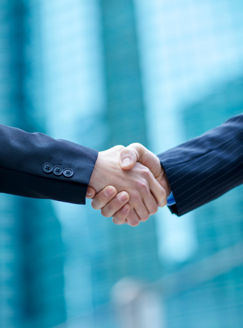 Une poignée de mains, peronnes qui portent un costard.