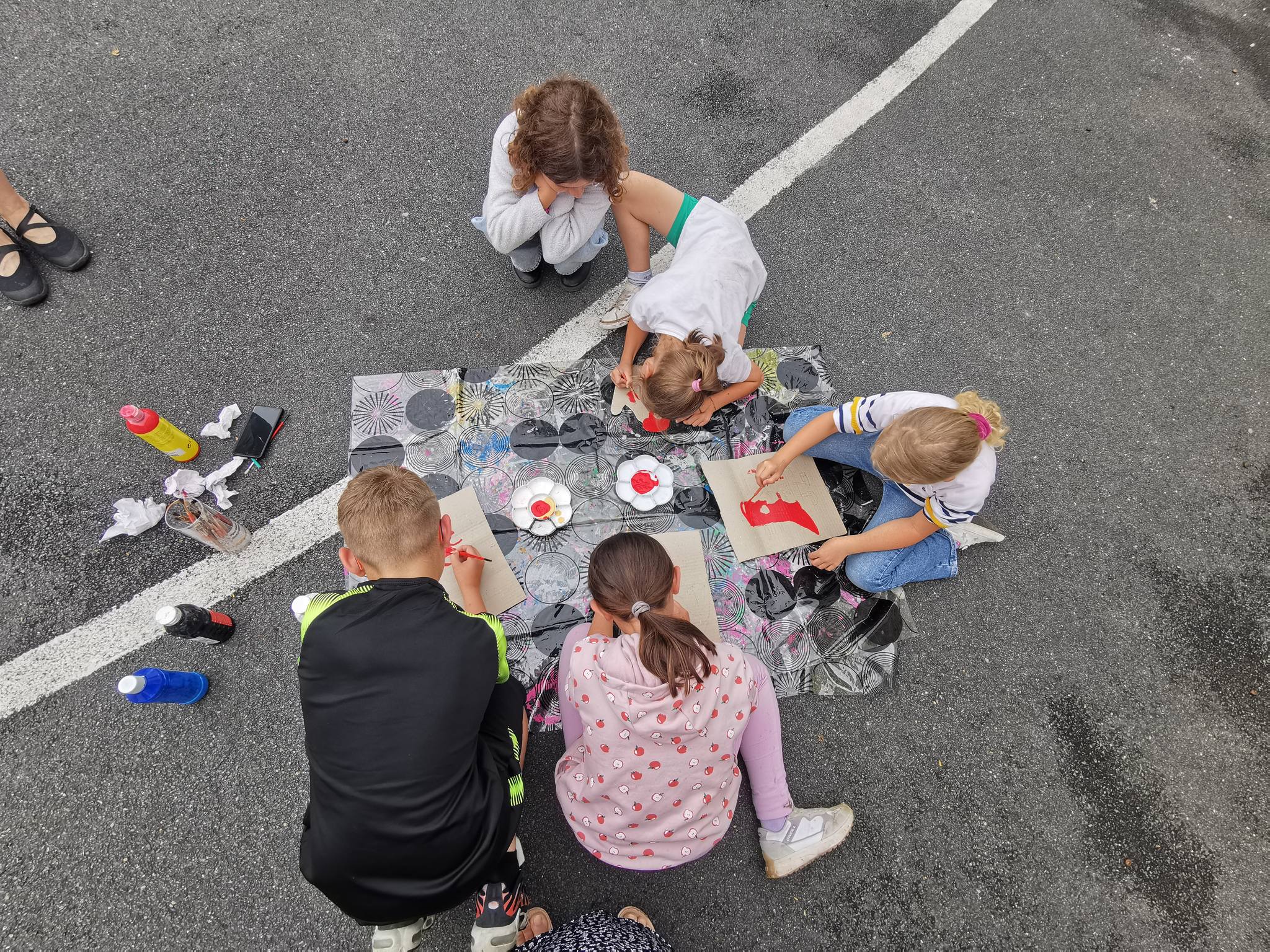 des enfants sont dans  une cours et réalise une activité manuelle et artistique ensemble