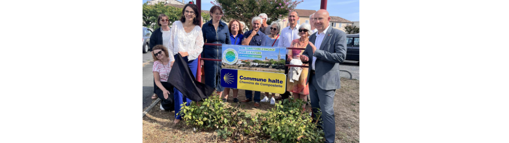 Des élus du territoire se tiennent devant le panneau "Communes Halte Chemin de Compostelles" de la commune de Sainte-Foy-la-Grande